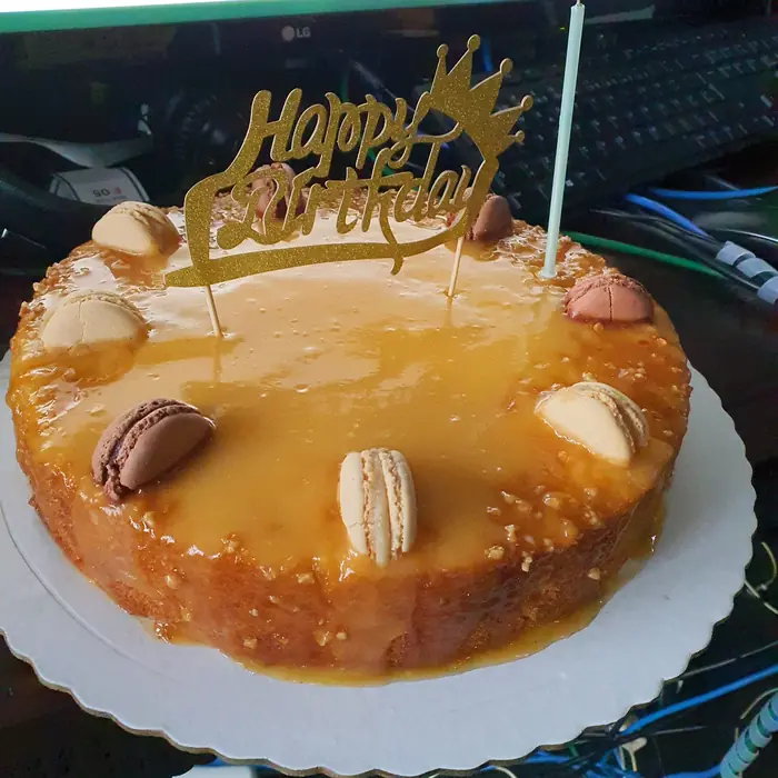 Bolo de caramelo com macarons e topo dourado de feliz aniversário